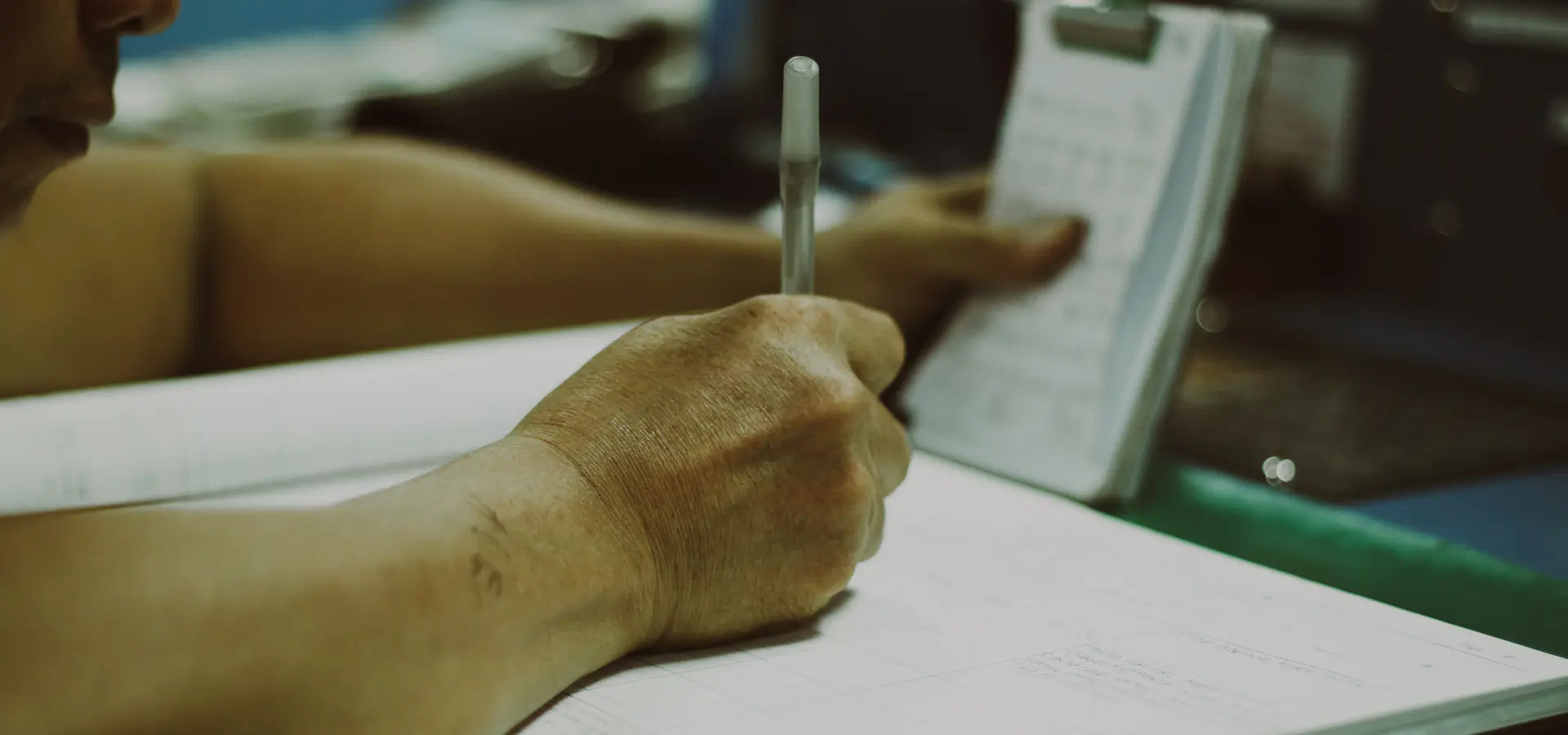 Hand checking off a paper checklist on a clipboard in a work area