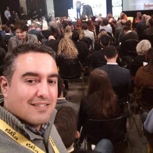 Selfie of Ignacio Segovia at a conference with a seated audience facing a stage behind him