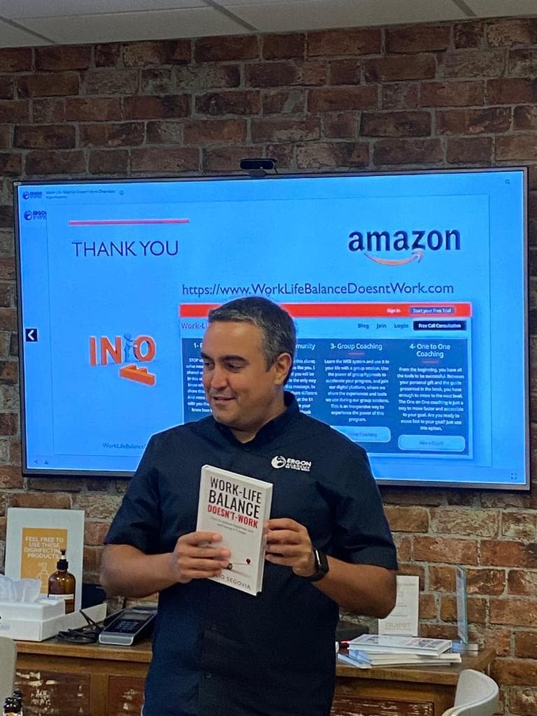 Ignacio Segovia holding a copy of his book in front of a presentation screen during a talk