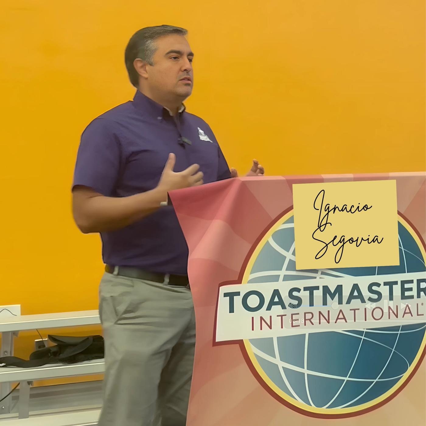 Ignacio Segovia speaking at a lectern draped with a Toastmasters International banner